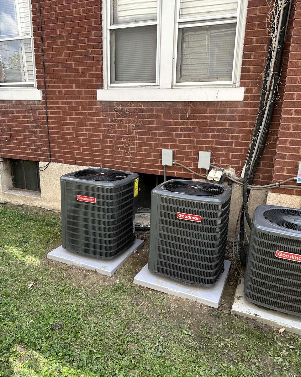 Three new condensing units installed side by side at a multi-unit home